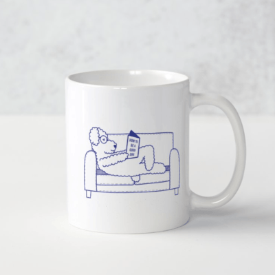 Tasse avec illustration de chien qui lit un livre sur un canapé
