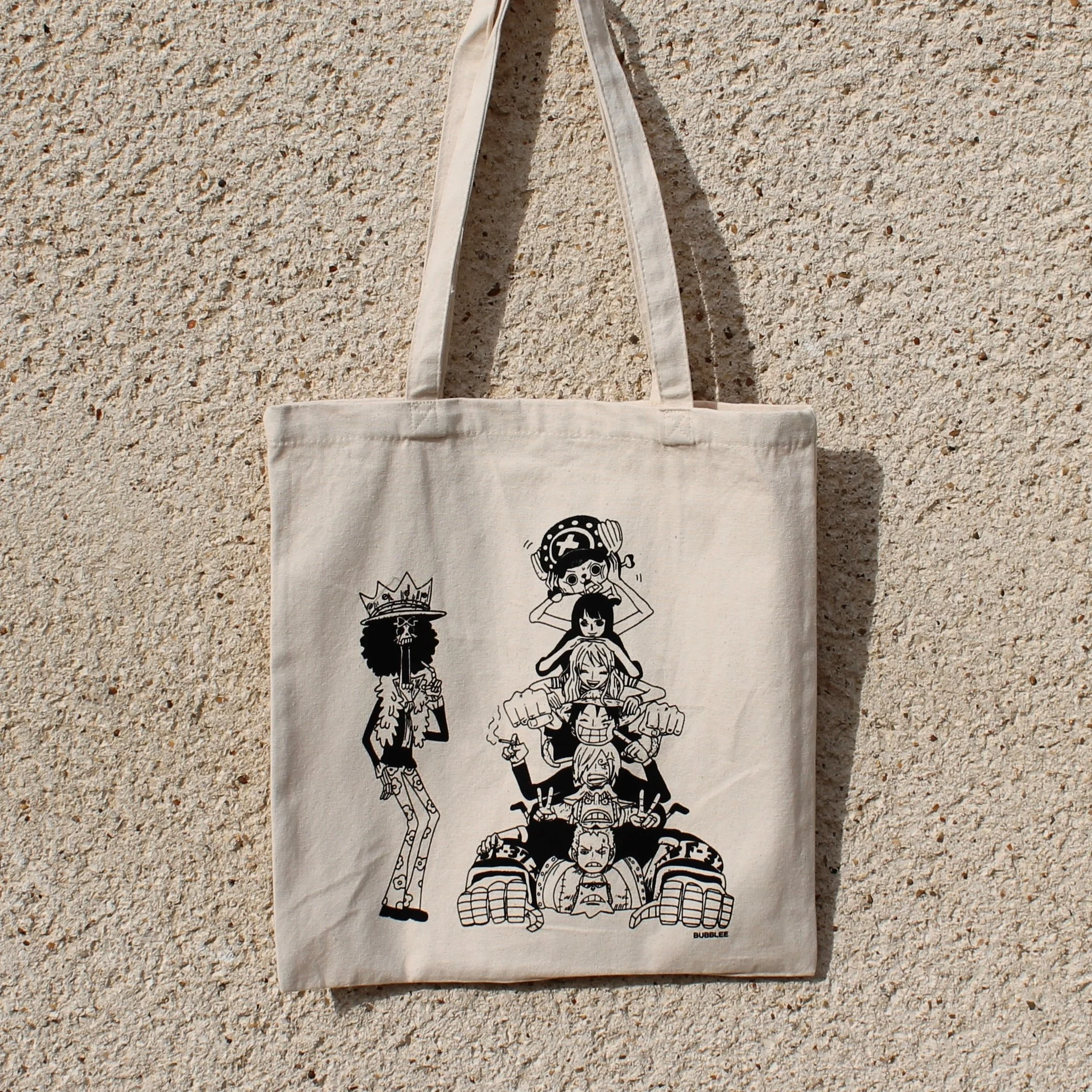 Tote bag One Piece imprimé noir sur blanc. Plusieurs personnages de l'équipage de One Piece. Franky, Zoro, Sanji, Luffy, Nami, Robin, Tony Tony Chopper, Brook.